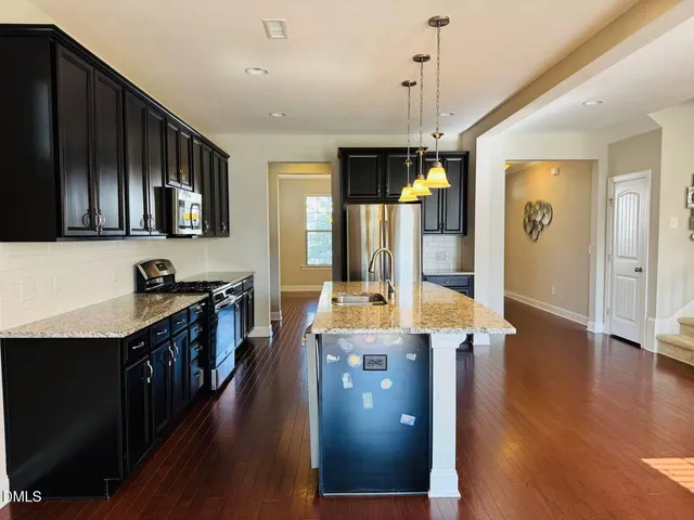 a open kitchen with stainless steel appliances granite countertop a stove refrigerator and wooden floor