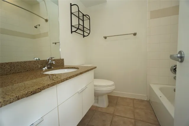 a bathroom with a granite countertop sink a toilet and mirror