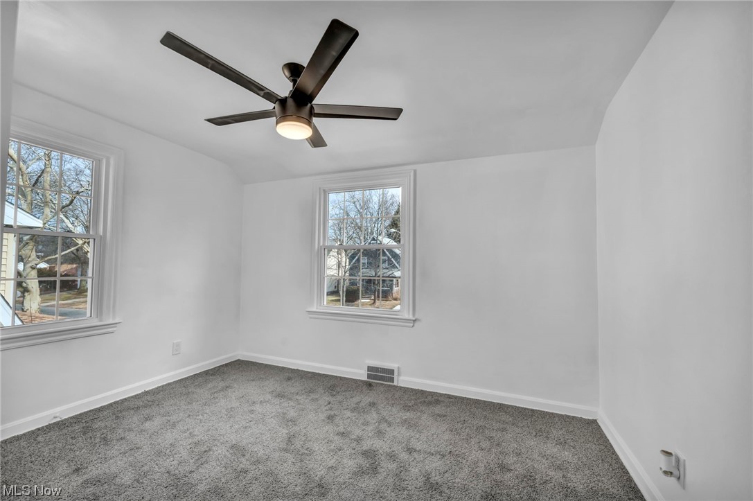 932 Englewood Road Cleveland Heights, OH 44121 - Photo 16 of 32 Empty room with a wealth of natural light, dark colored carpet, and ceiling fan