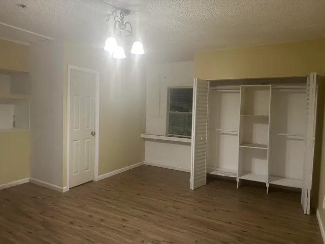 an empty room with wooden floor closet and windows