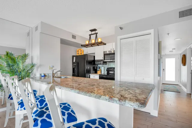 a kitchen with a sink a counter top space and living room view