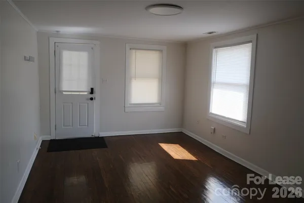 an empty room with wooden floor and windows