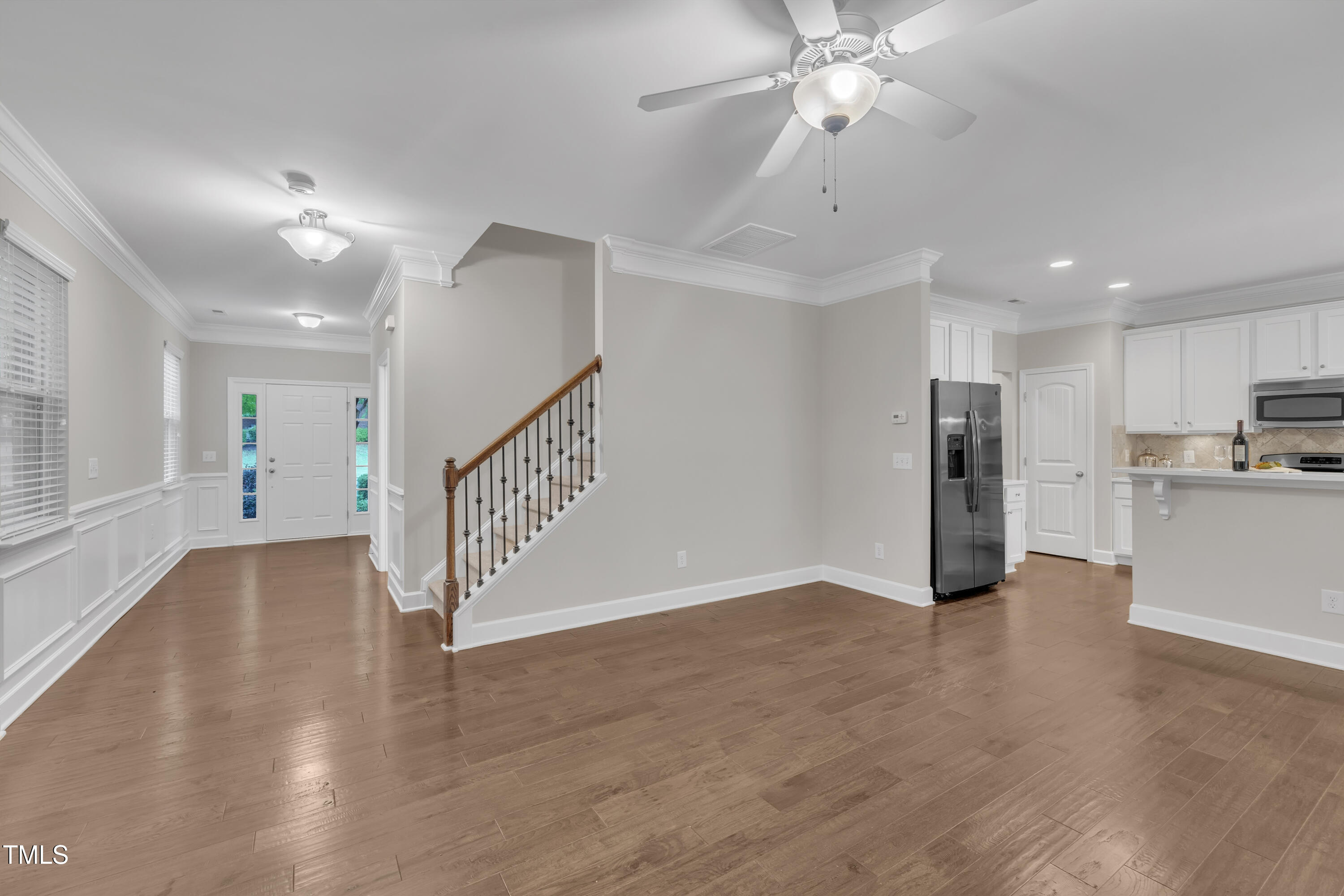 2073 Weston Green Loop Cary, NC 27513 - Photo 10 of 52 a view of an empty room with wooden floor a ceiling fan and kitchen space