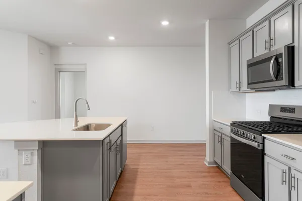 a kitchen with stainless steel appliances a stove top oven a sink dishwasher and a refrigerator with wooden floor