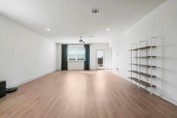 an empty room with wooden floor and windows