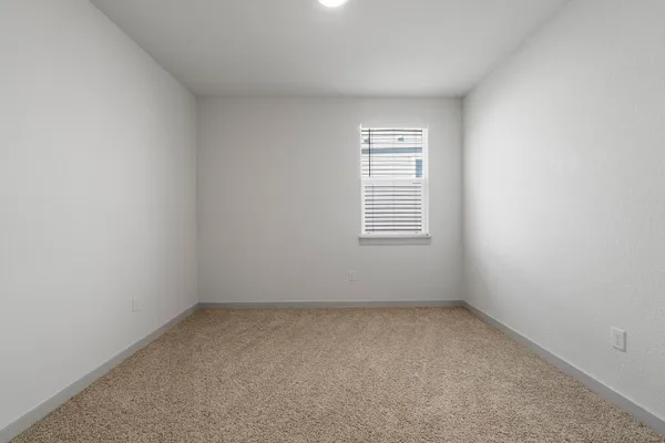 an empty room with a window and ceiling fan