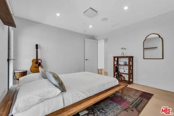 a bedroom with a bed a dresser and wooden floor