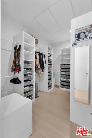 a view of walk in closet with clothes and shoes