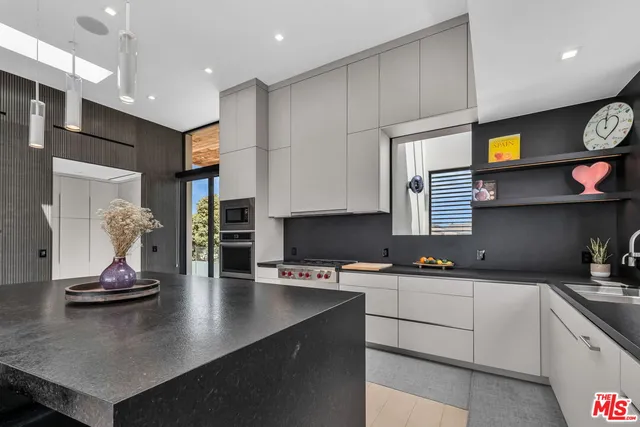 a kitchen with stainless steel appliances a sink a stove and white cabinets