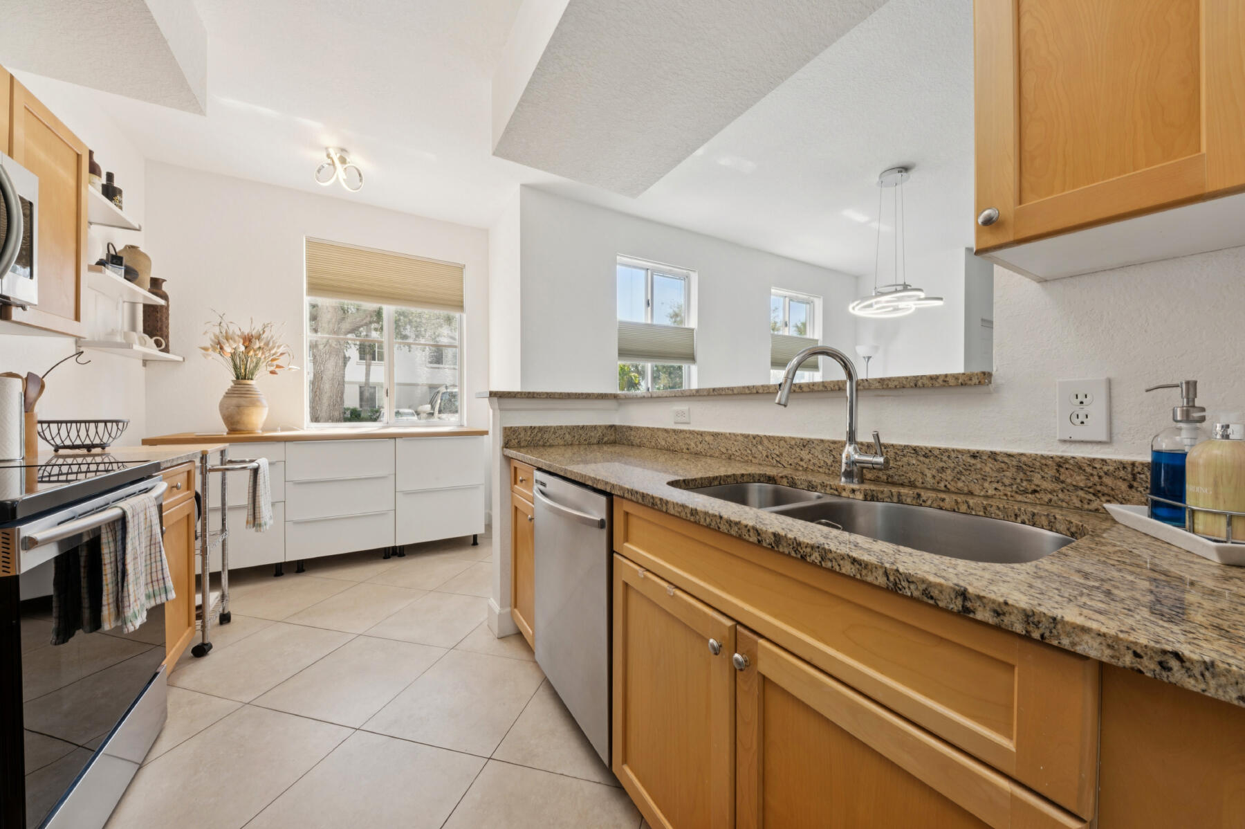 11022 Legacy Drive, Unit 101 Palm Beach Gardens, FL 33410 - Photo 6 of 16 a kitchen with granite countertop a sink stove and cabinets