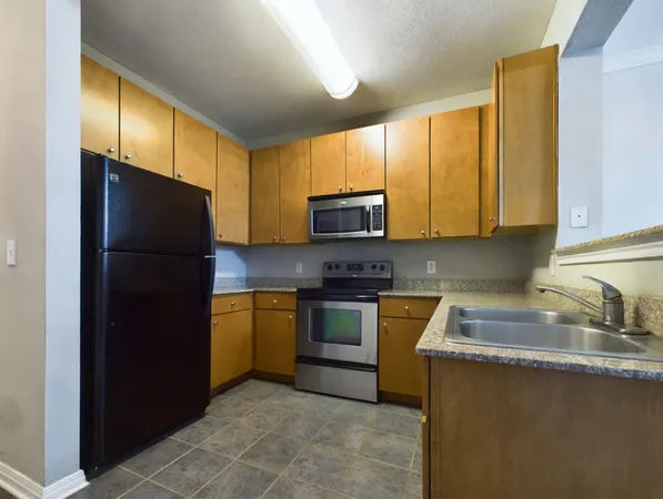 a kitchen with a refrigerator a microwave a sink and cabinets