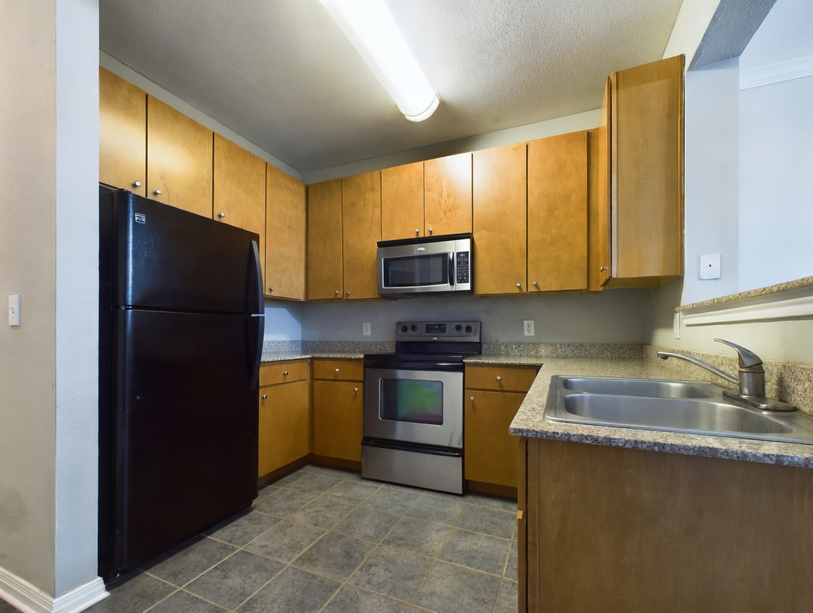 2502 Leon Street, Unit 100 Austin, TX 78705 - Photo 3 of 23 a kitchen with a refrigerator a microwave a sink and cabinets