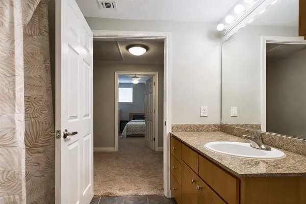 a en suite bathroom with a granite countertop sink and a mirror