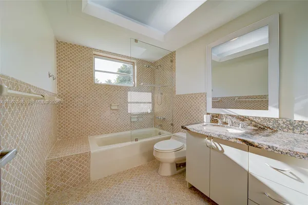 a bathroom with a granite countertop sink mirror vanity bathtub and toilet