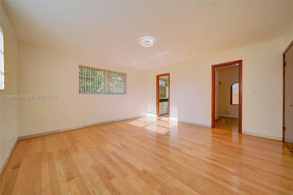 an empty room with wooden floor and windows