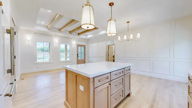 a hall with kitchen island white cabinets and wooden floor