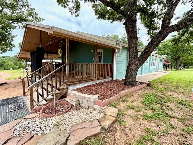 a view of a house with wooden deck and a large tree