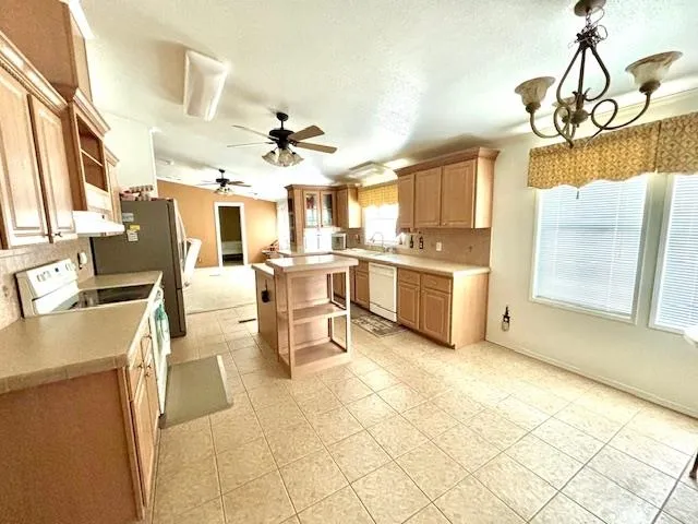 a view of a kitchen with kitchen island stainless steel appliances a stove a table and chairs in it