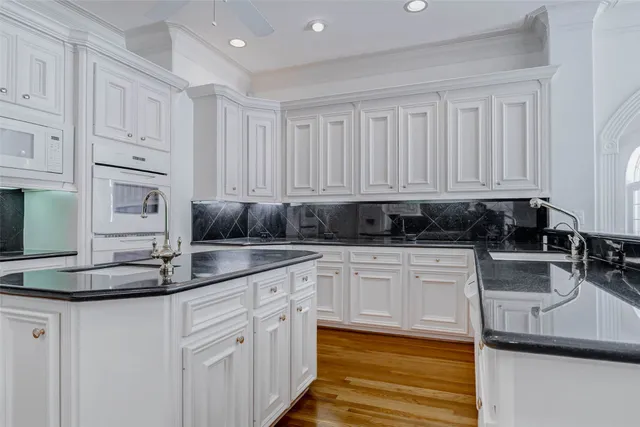 a kitchen with stainless steel appliances granite countertop a sink a stove and white cabinets