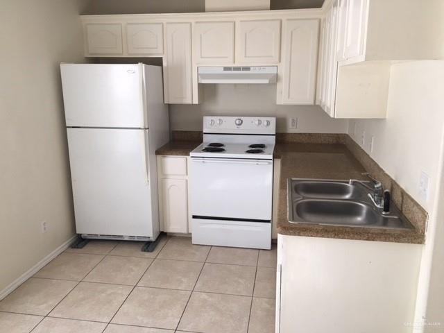 401 Rockport Street Alton, TX 78573 - Photo 5 of 11 Kitchen with white appliances, dark countertops, white cabinets, and under cabinet range hood