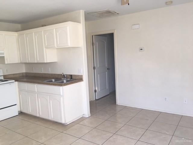 401 Rockport Street Alton, TX 78573 - Photo 6 of 11 Kitchen featuring dark countertops, white range with electric cooktop, white cabinets, light tile patterned flooring, and ventilation hood