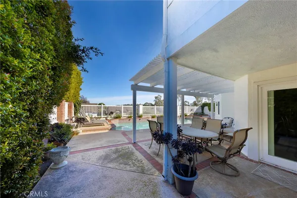 a view of a patio with table and chairs potted plants and floor to ceiling window