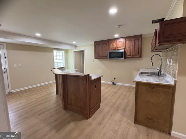 a kitchen with kitchen island granite countertop a sink a stove top oven a refrigerator with wooden floors and cabinets