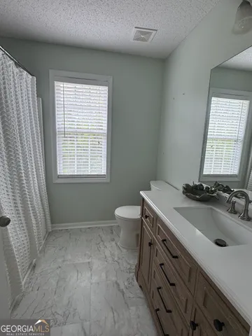 a bathroom with a sink toilet double vanity and window
