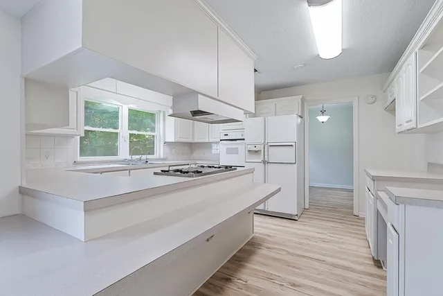 a kitchen with a sink a stove and white cabinets