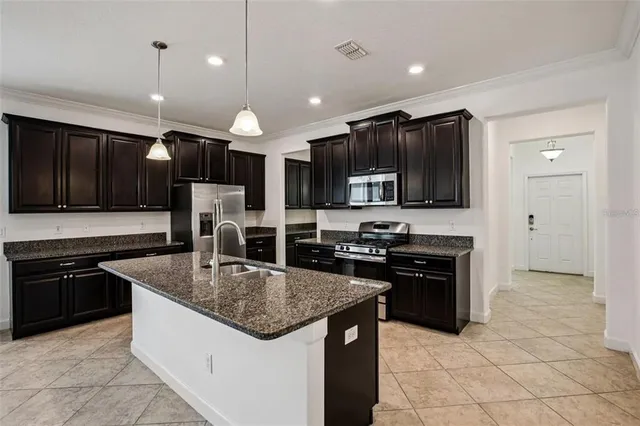 a kitchen with stainless steel appliances granite countertop a sink a stove top oven a counter space and cabinets