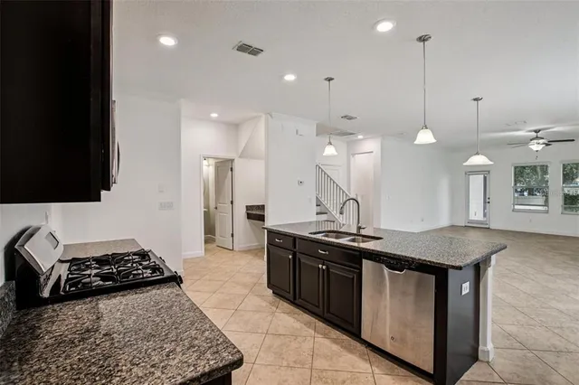 a kitchen with stainless steel appliances granite countertop a sink a stove and a wooden floors