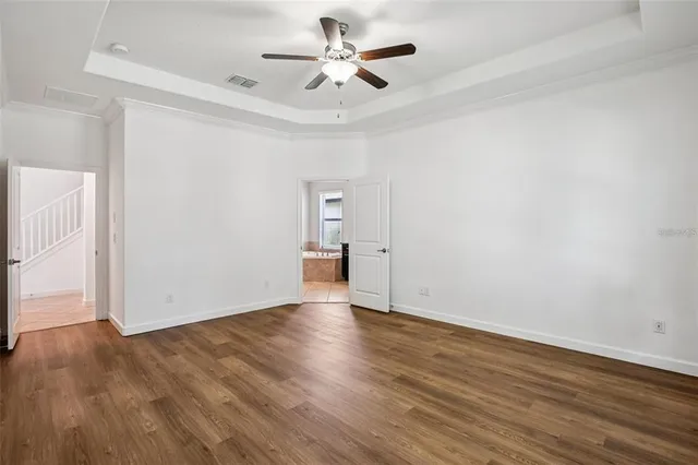 an empty room with wooden floor and a ceiling fan