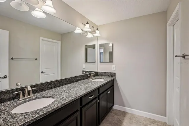 a bathroom with a granite countertop double vanity sink and a mirror