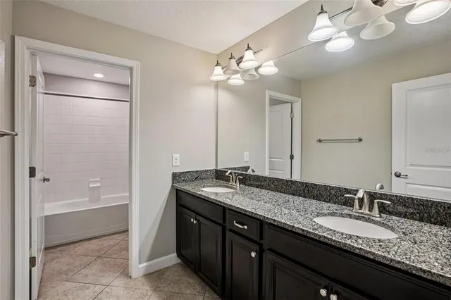 a bathroom with a granite countertop sink a light fixture and a mirror