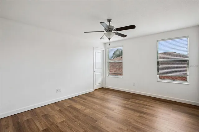 a view of an empty room with wooden floor and a window