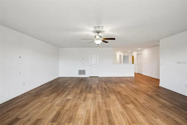 a view of empty room with wooden floor and ceiling fan