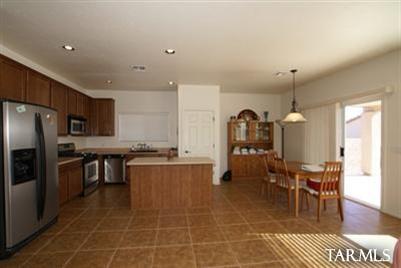 3624 East Mecate Road Tucson, AZ 85739 - Photo 10 of 17 a kitchen with stainless steel appliances granite countertop a stove top oven a sink dishwasher a dining table and chairs with wooden floor