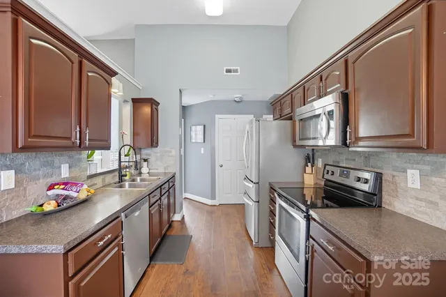 a kitchen with stainless steel appliances granite countertop a sink stove and cabinets