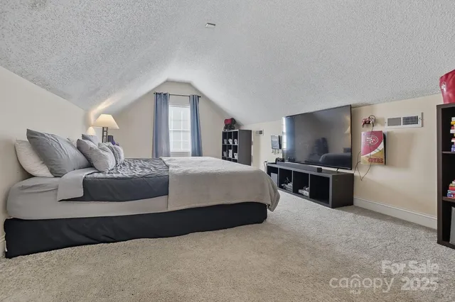 a spacious bedroom with a bed and a flat screen tv