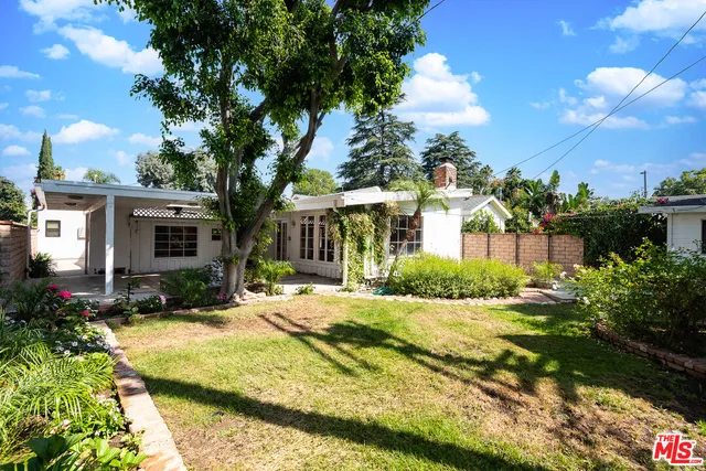 a view of a house with a small yard and potted plants