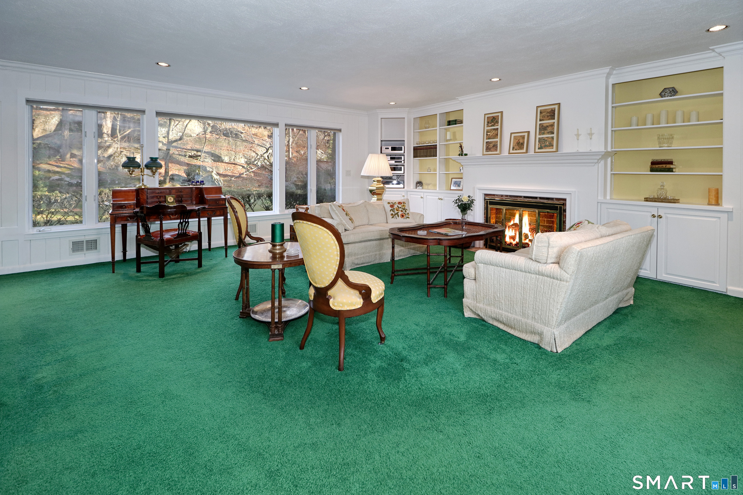 5 Over Rock Lane Westport, CT 06880 - Photo 9 of 28 Living room area with wood burning fireplace, built-ins and wall of windows overlooking private backyard.