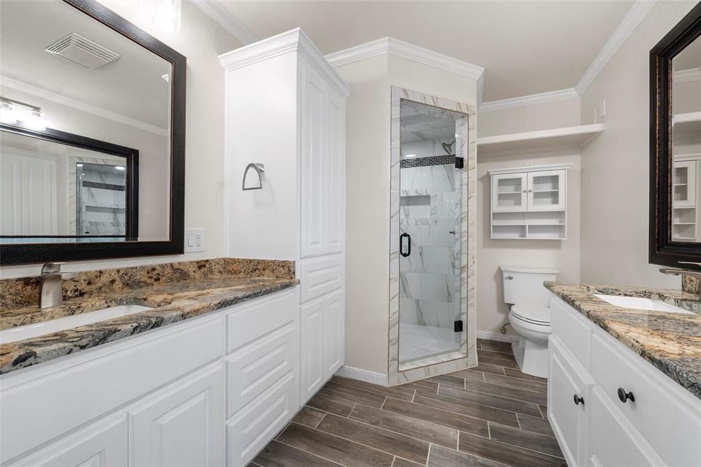 5112 Old Caufield Ranch Road McGregor, TX 76657 - Photo 23 of 38 Full bathroom with wood finish floors, a shower stall, two vanities, and crown molding