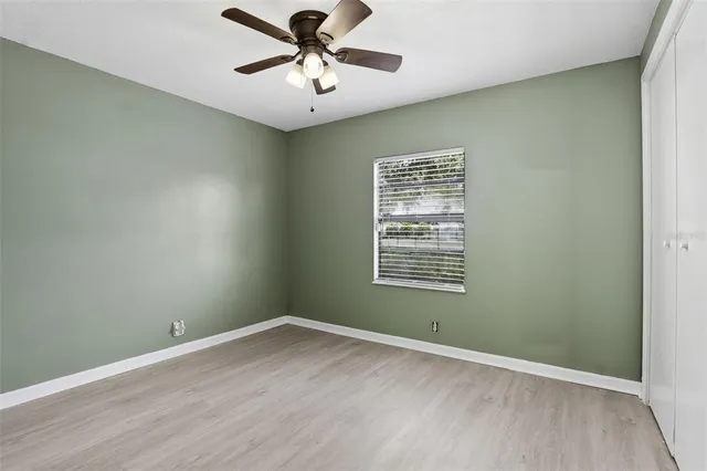 an empty room with a window and a fan