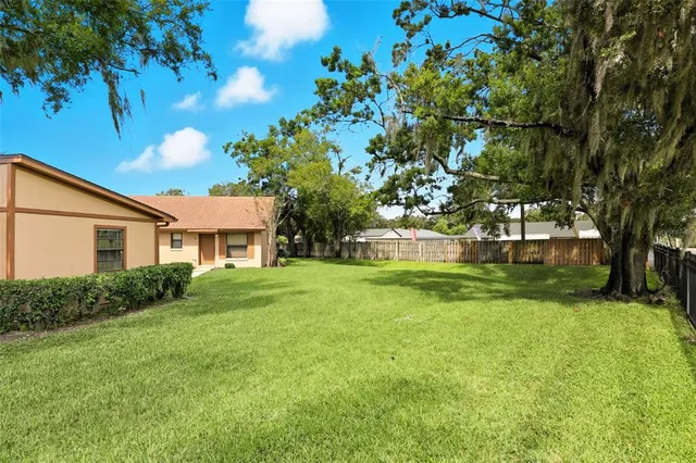 a view of a house with a big yard and large trees
