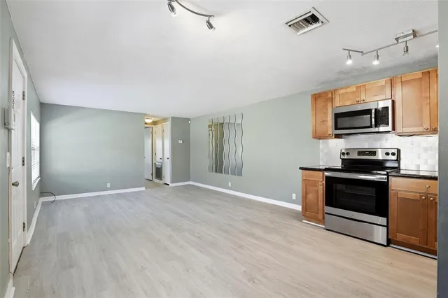 a view of a kitchen with a sink stove cabinets and empty room
