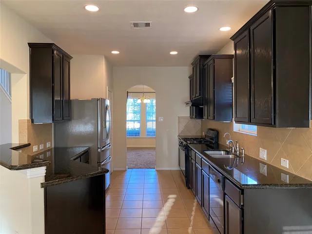 a kitchen with stainless steel appliances granite countertop a refrigerator a stove and a sink