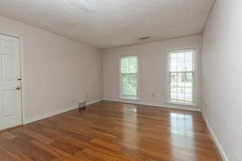 an empty room with wooden floor and windows