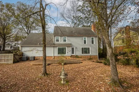 a backyard of a house with large trees and wooden fence