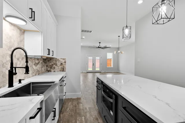 a kitchen with stainless steel appliances granite countertop a sink stove a refrigerator and white cabinets with wooden floor