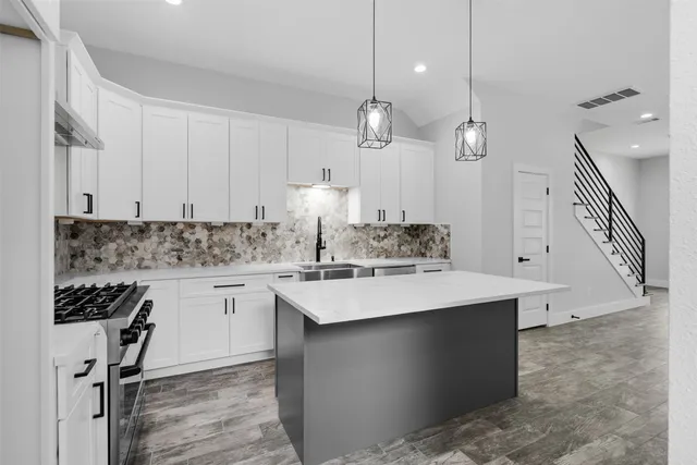 a large kitchen with granite countertop a white stove top oven and white cabinets